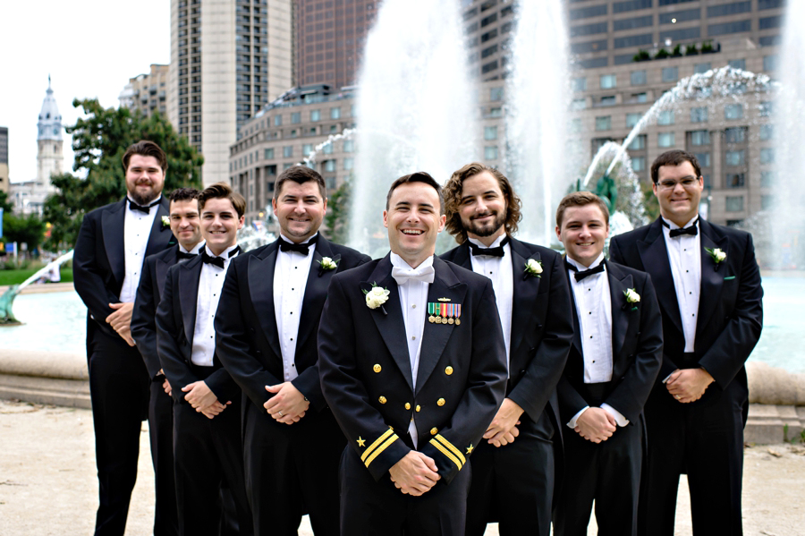 A groom and his groomsmen stand in front of the fountain at Logan Square.
